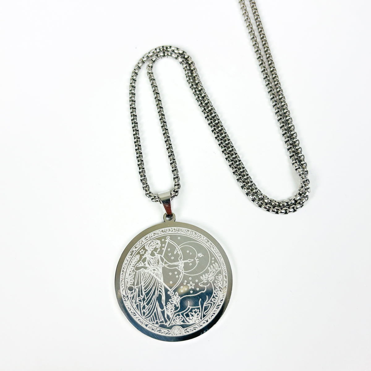 A silver-toned pendant necklace featuring an engraved circular medallion with a celestial and botanical design, displayed on a clean white background.