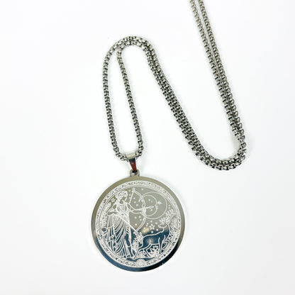 A silver-toned pendant necklace featuring an engraved circular medallion with a celestial and botanical design, displayed on a clean white background.