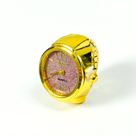 A gold-colored ring-shaped quartz watch with a glittery pink face and gold-tone hands and numerals, set against a plain white background.