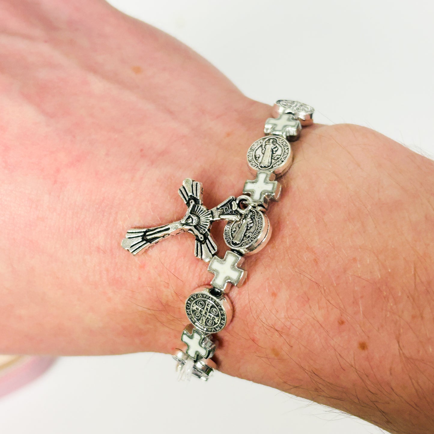 Silver bracelet with charms on a wrist against a white background