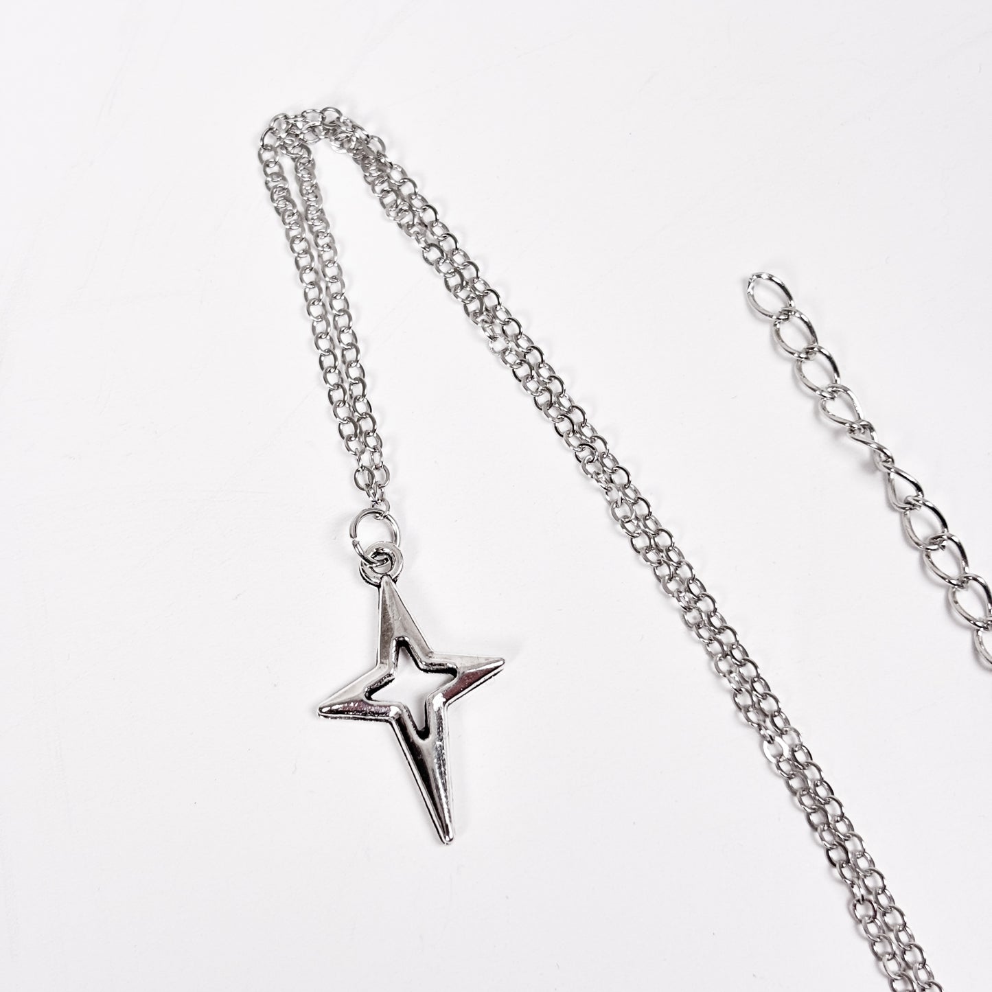 Silver chain necklace with a star pendant on a white background