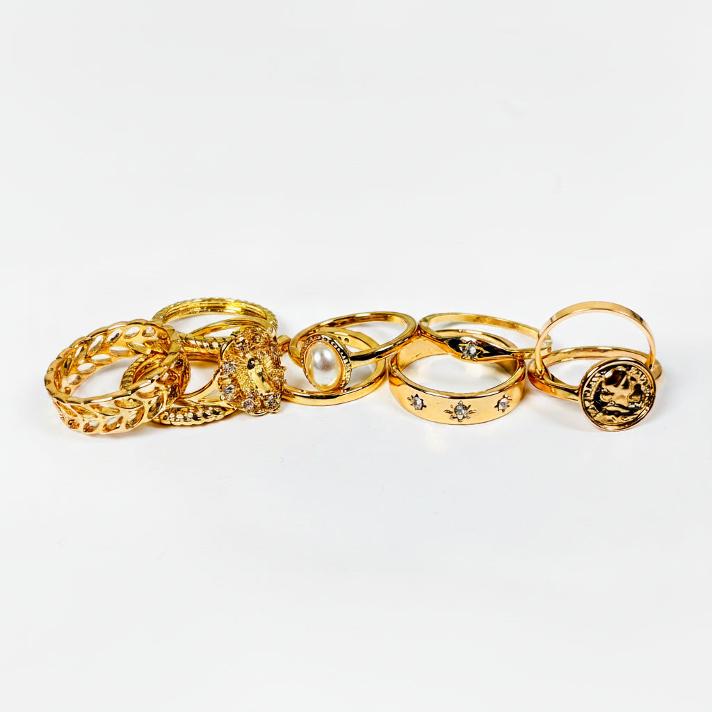 Set of gold rings with various designs on a light gray background