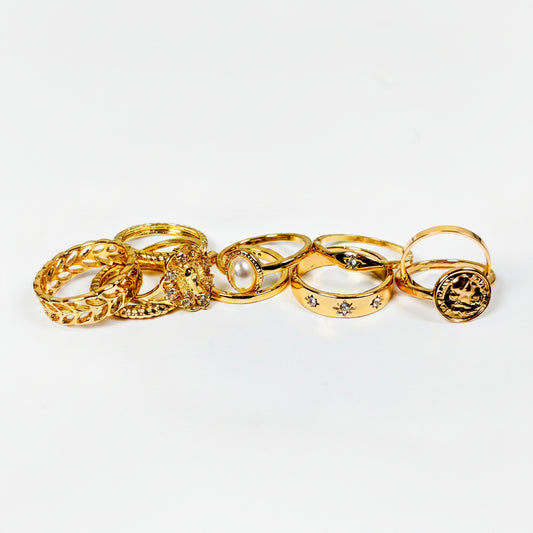 Set of gold rings with various designs on a light gray background