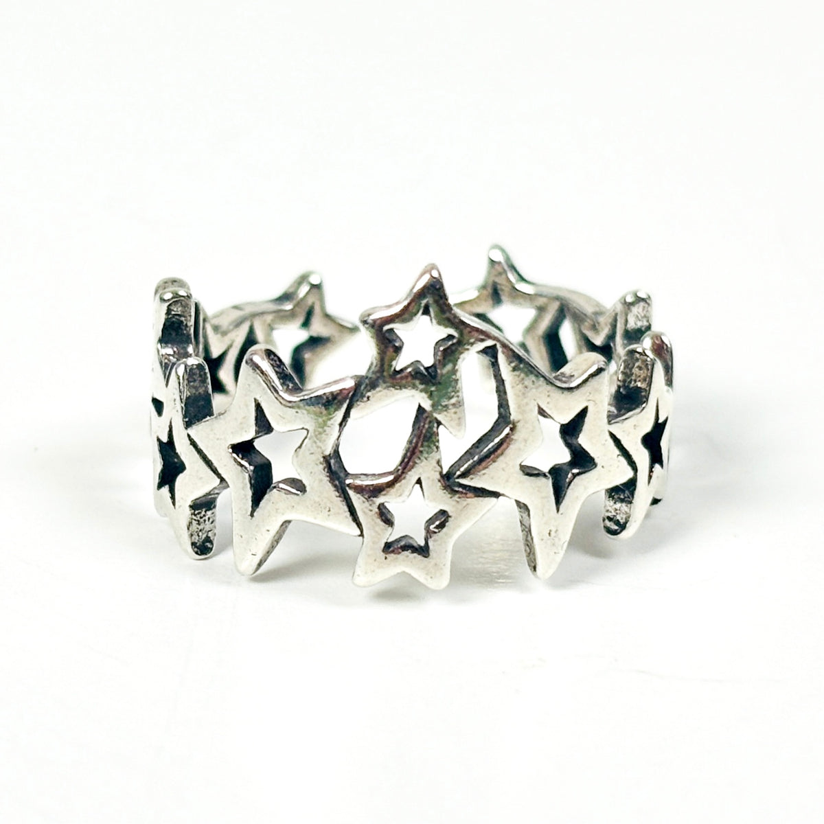 A sterling silver band ring featuring a series of interlocking star cutouts, photographed on a seamless white background.