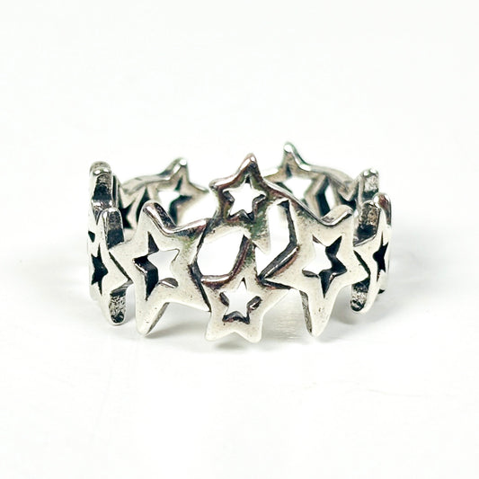 A sterling silver band ring featuring a series of interlocking star cutouts, photographed on a seamless white background.