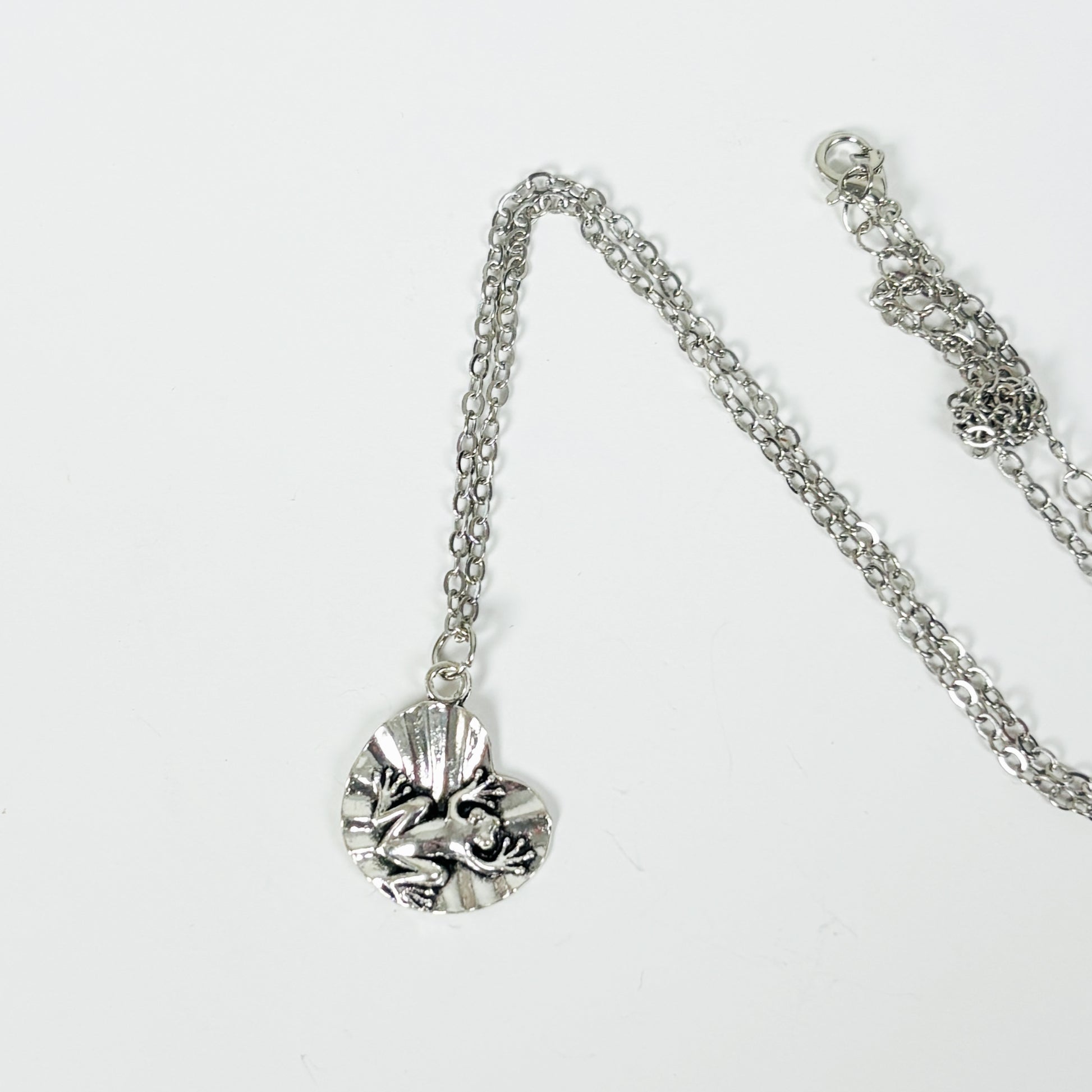Silver necklace with a detailed pendant on a white background