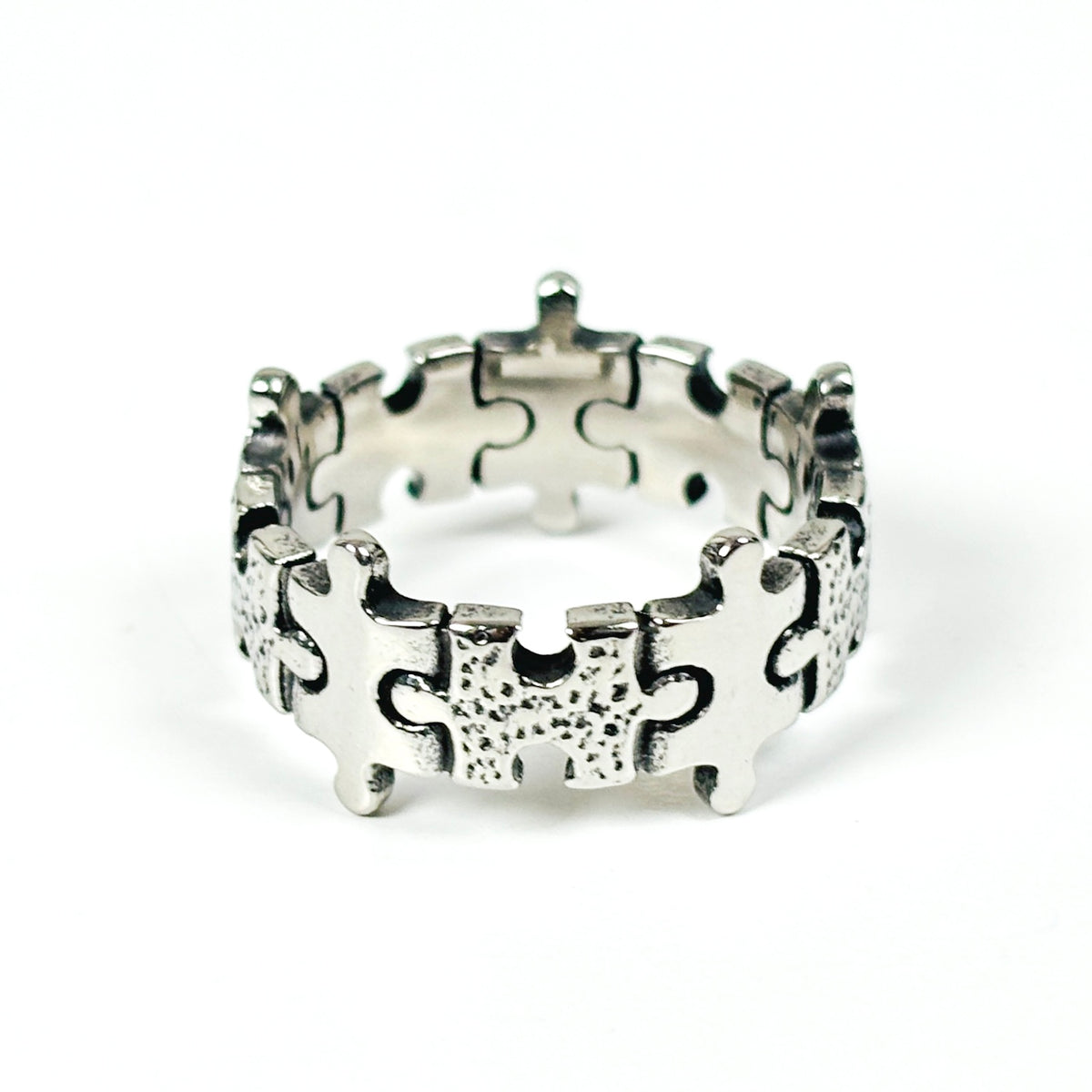 A sterling silver puzzle ring with interlocking puzzle piece details, photographed on a clean white background.