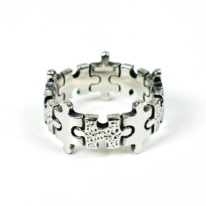 A sterling silver puzzle ring with interlocking puzzle piece details, photographed on a clean white background.