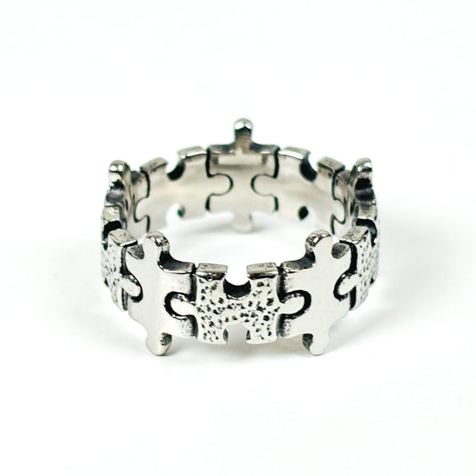 A sterling silver puzzle ring with interlocking puzzle piece details, photographed on a clean white background.