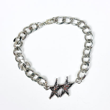 A silver-tone chain link bracelet featuring two interlocking star charms, one with a small pink stone accent, displayed on a clean white background.