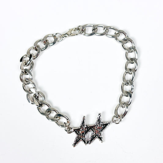A silver-tone chain link bracelet featuring two interlocking star charms, one with a small pink stone accent, displayed on a clean white background.