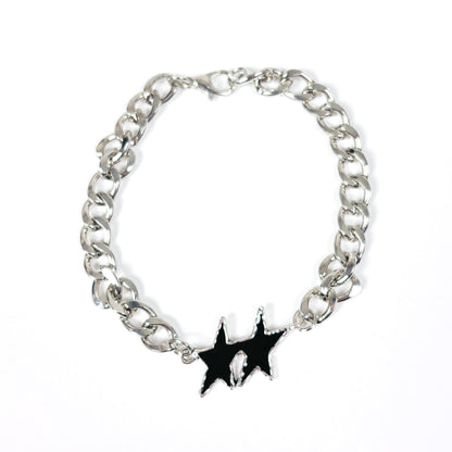 A silver-tone metal chain bracelet with a black enamel starburst charm featuring a small white skull detail in the center, displayed on a clean white background.