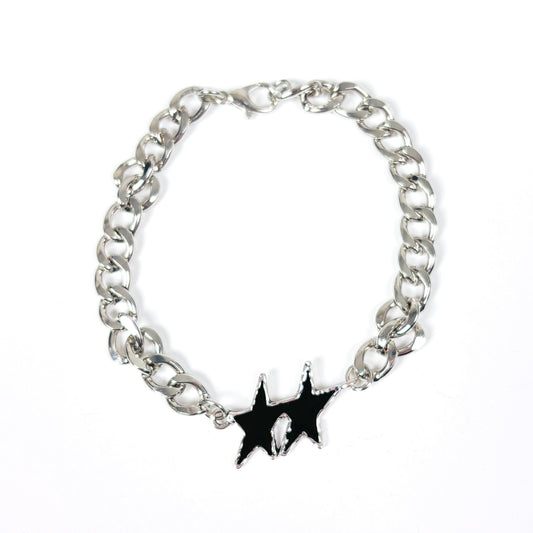 A silver-tone metal chain bracelet with a black enamel starburst charm featuring a small white skull detail in the center, displayed on a clean white background.