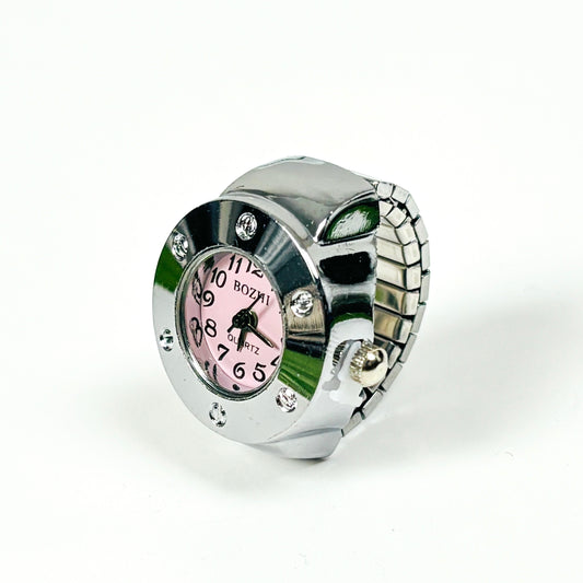 A silver-tone metal watch with a pink dial and rhinestone accents, photographed on a plain white background.