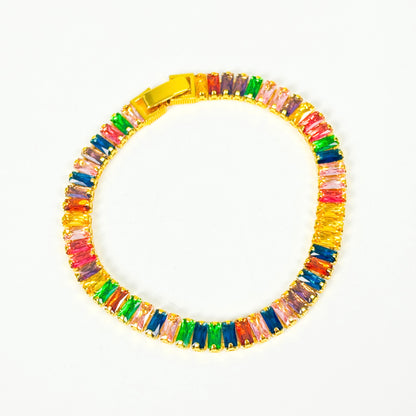 A gold-plated tennis bracelet featuring a row of colorful, rectangular baguette-cut crystals in shades of pink, green, blue, orange, and purple, displayed on a clean white background.