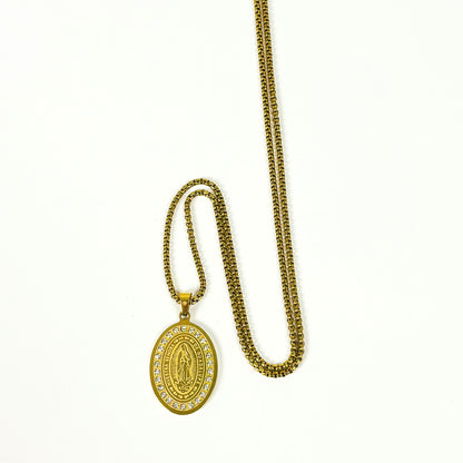 A gold-toned religious pendant necklace featuring an oval Miraculous Medal pendant adorned with small clear stones, displayed on a clean white background.