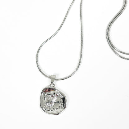 A silver snake chain necklace with an irregular, organic-shaped polished silver pendant, displayed on a clean white background.