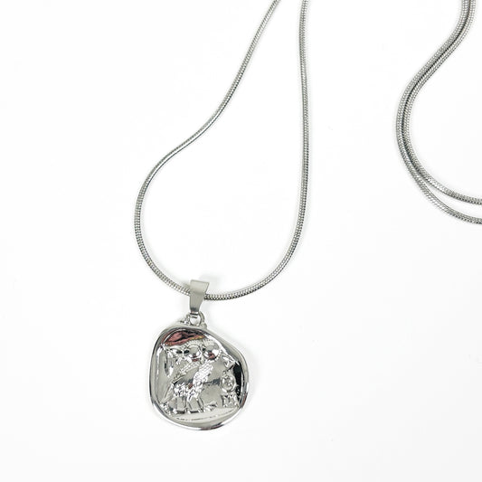 A silver snake chain necklace with an irregular, organic-shaped polished silver pendant, displayed on a clean white background.