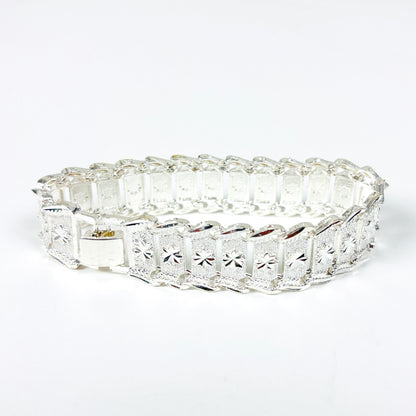 A silver bracelet with rectangular pavé-set clear stones and a starburst motif on each panel, shown on a plain white background.